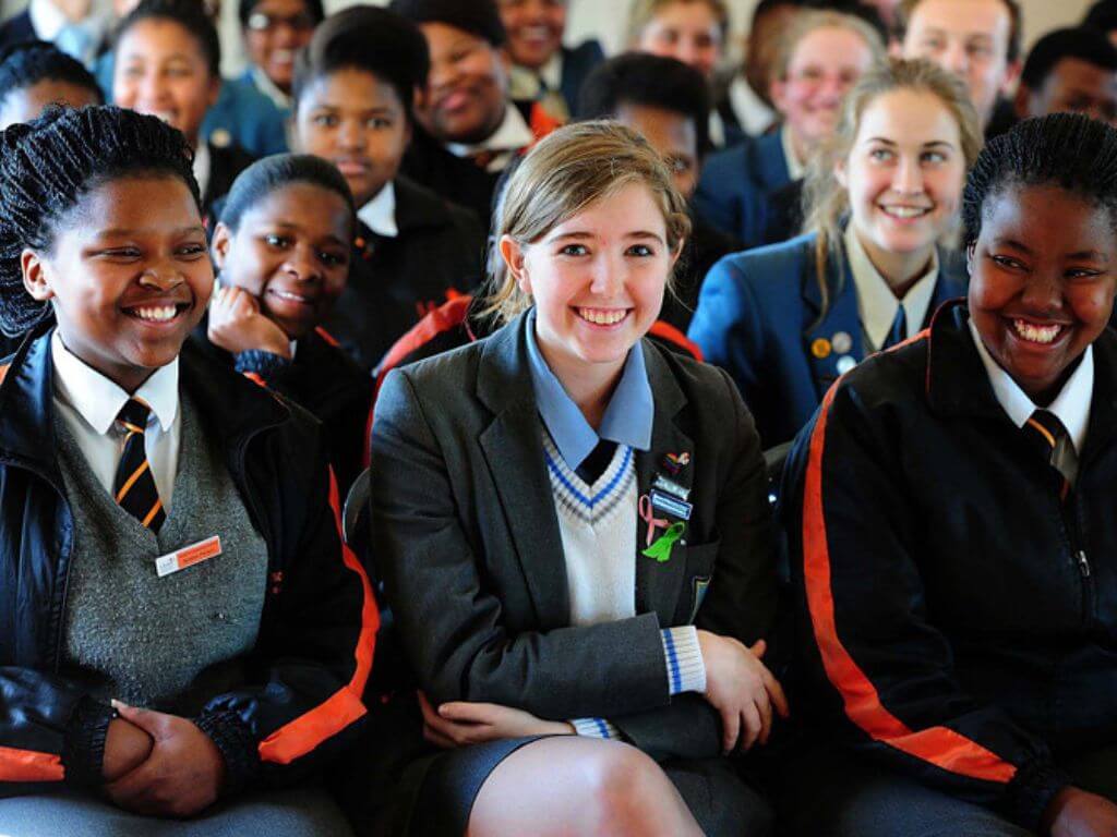 Inclusive group of happy matric students in school uniforms, seated and smiling in a classroom setting.