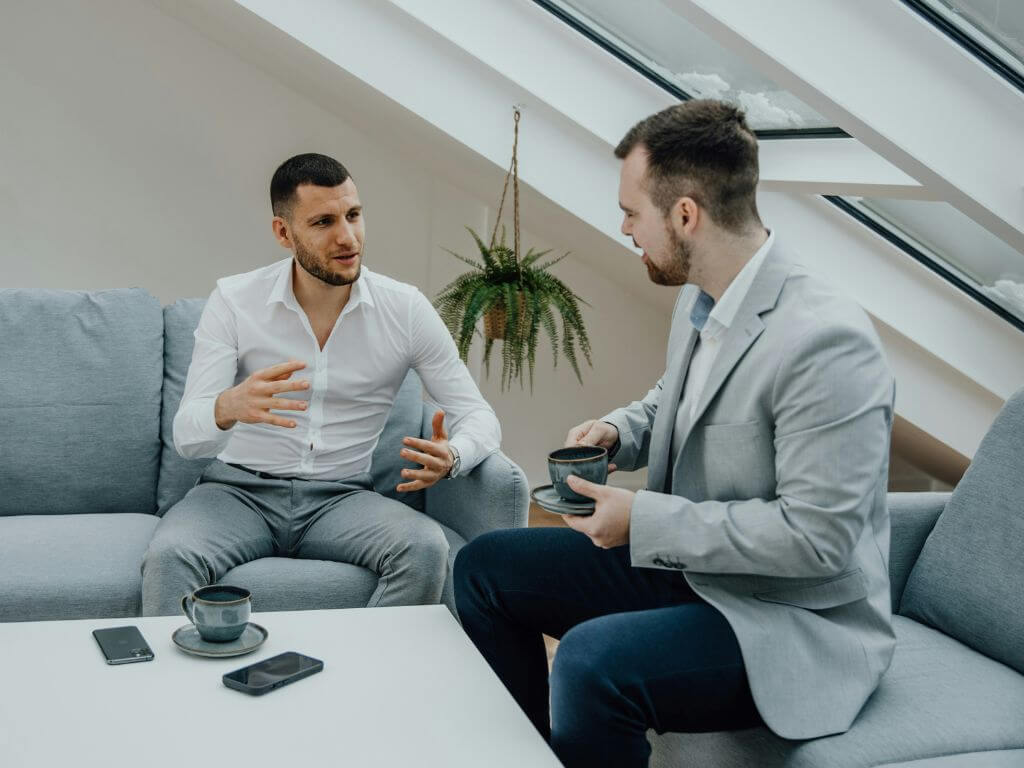 Two businessmen having a discussion over coffee in a modern office setting.